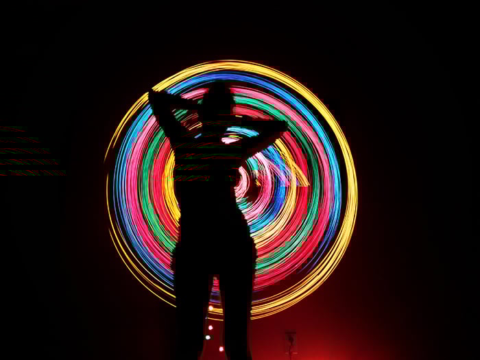 Colorful light graffiti behind the silhouette of a woman.