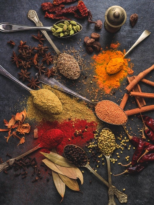 Indian food photography with spoons and spices scattered on a table
