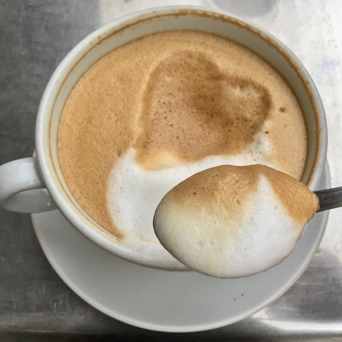 Close up of spooning coffee foam from a cappuccino