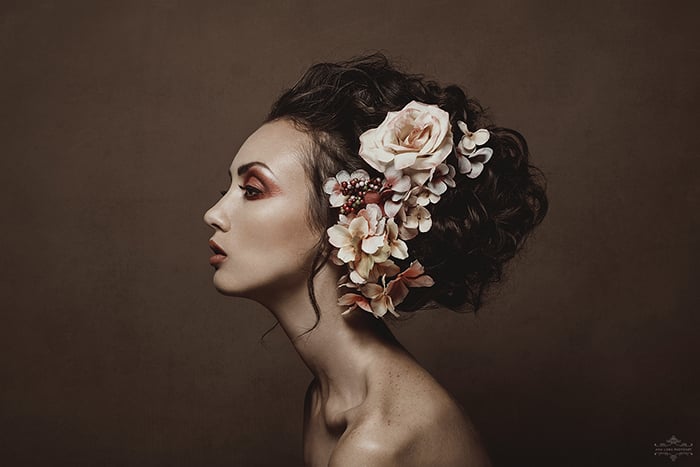 Side fine-art portrait of a woman with flowers in her hair