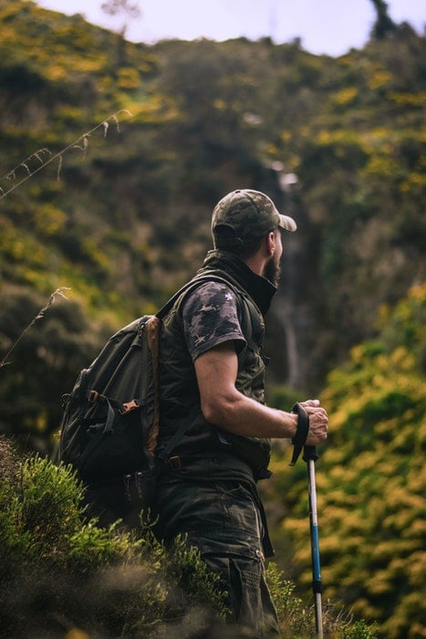 A camouflaged nature photographer on a hike in the wilderness