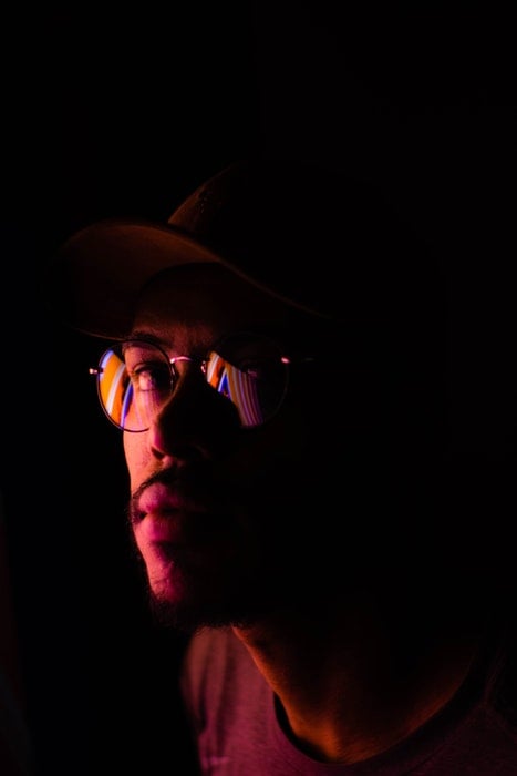 A man wearing glasses with a dark background.
