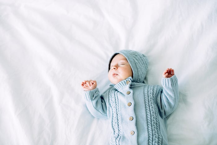 A baby sleeping on a white bed.