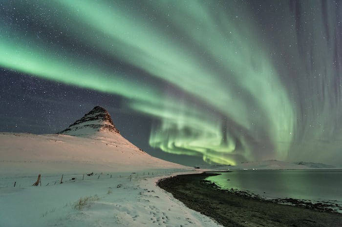 aurora borealis photographed shining above a snowy landscape