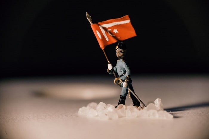 miniature photography of a soldier carrying a flag through snow