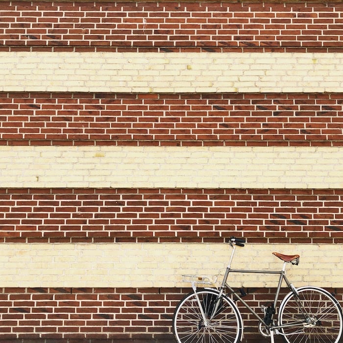 Repetition in photography: A bike leaning up against a wall with repetition of brick patterns