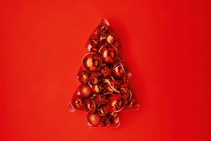 Christmas flat lay with tree made from jingle bells on red background