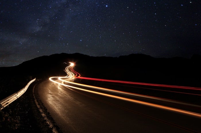 using a time-lapse calculator for time-lapse photos: light streaks from moving cars illuminate a dark road during the night