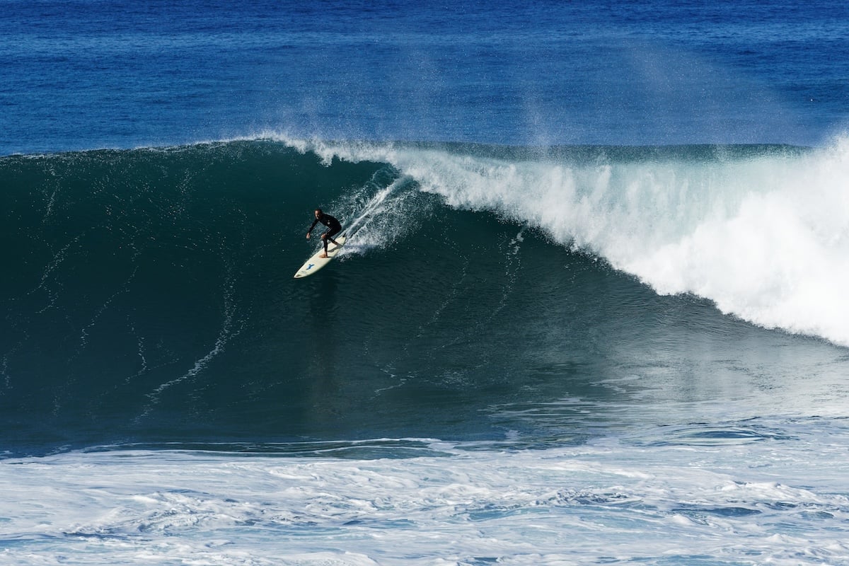 A rider at the top part of a barrel wave with the ocean in the background as an example of surf photography