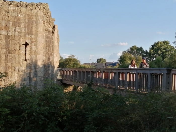Two people walking across a bridge next to a castle Two people walking across a bridge next to a castle