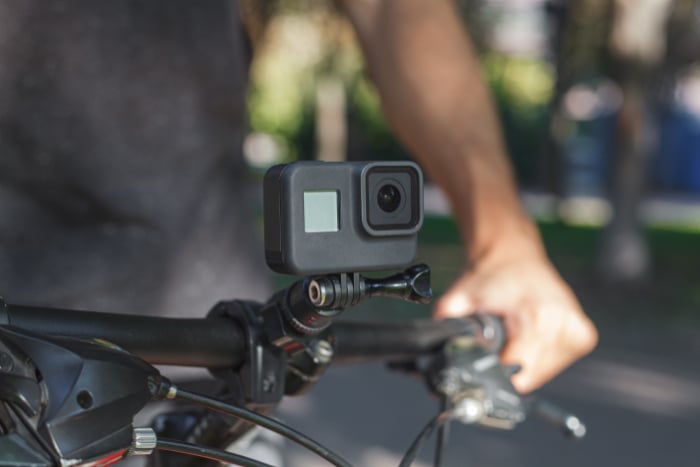 Action camera mounted on the handlebar of a bicycle that a male cyclist is holding Action camera mounted on the handlebar of a bicycle that a male cyclist is holding