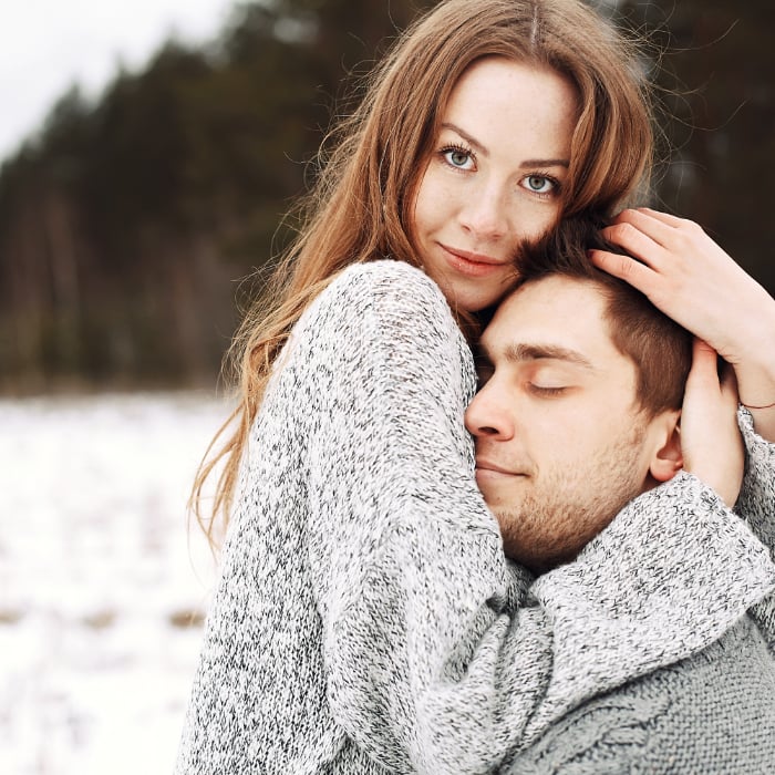 Young couple hugging against a snowy landscape Young couple hugging against a snowy landscape