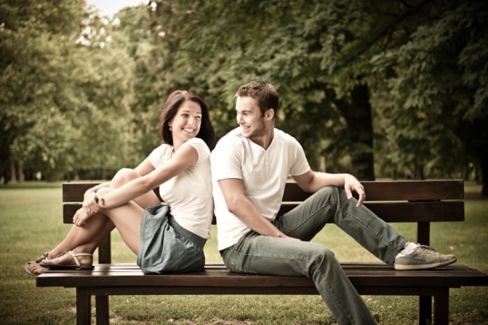 Young couple in coordiated clothes sitting smiling at each other on a bench Young couple in coordiated clothes sitting smiling at each other on a bench