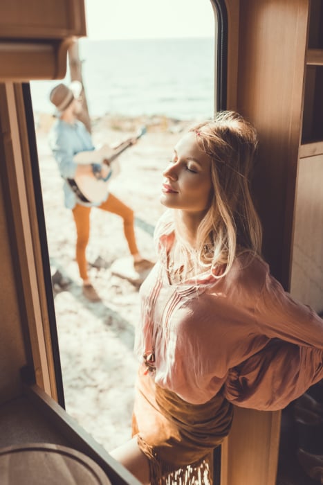 Young woman in doorway, with an out-of-focus man outside playing the guitar Young woman in doorway, with an out-of-focus man outside playing the guitar