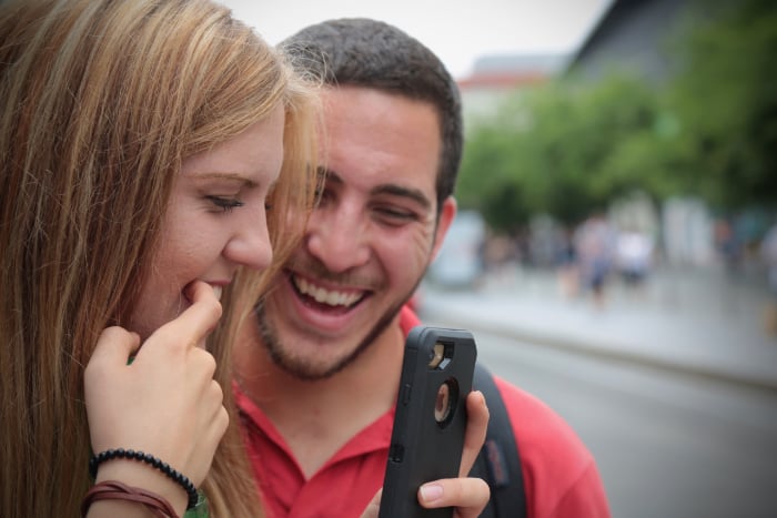 Young couple checking how they look in their phone before a photo Young couple checking how they look in their phone before a photo
