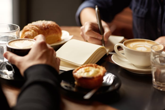 Close-up of someone writing a list in a coffee shop Close-up of someone writing a list in a coffee shop