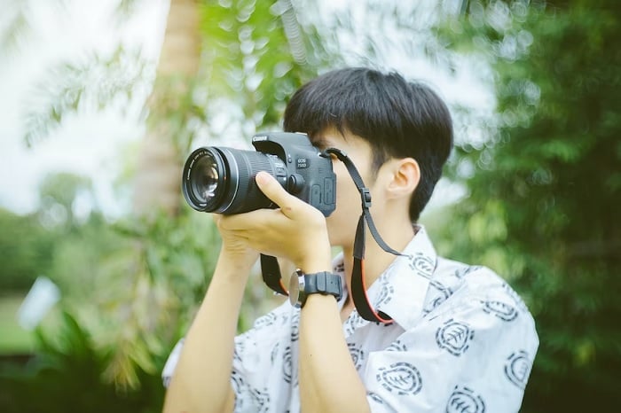 Young man holding a camera to his face Young man holding a camera to his face