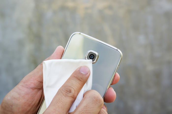Man cleaning his smartphone with a microfiber cloth Man cleaning his smartphone with a microfiber cloth
