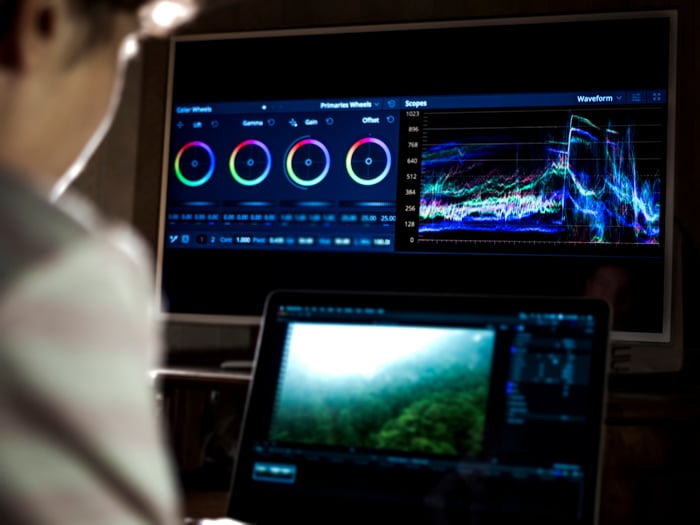 A person is sitting in front of a computer monitoring video footage.