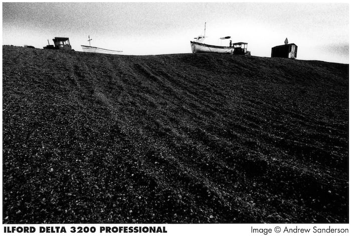 A plowed field, with two farm vehicles on it.
