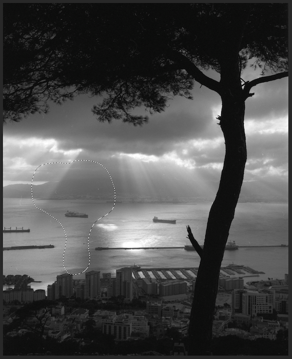 An old town with mountains in the background, under a cloudy sky.