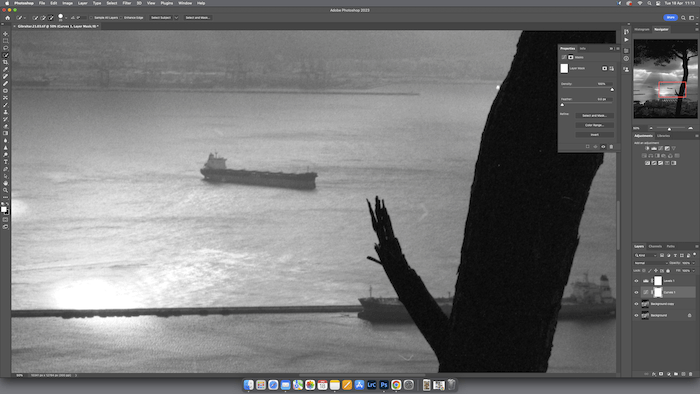 A body of water during sunset or sunrise, with a ship in the distance and a cityscape on the horizon.