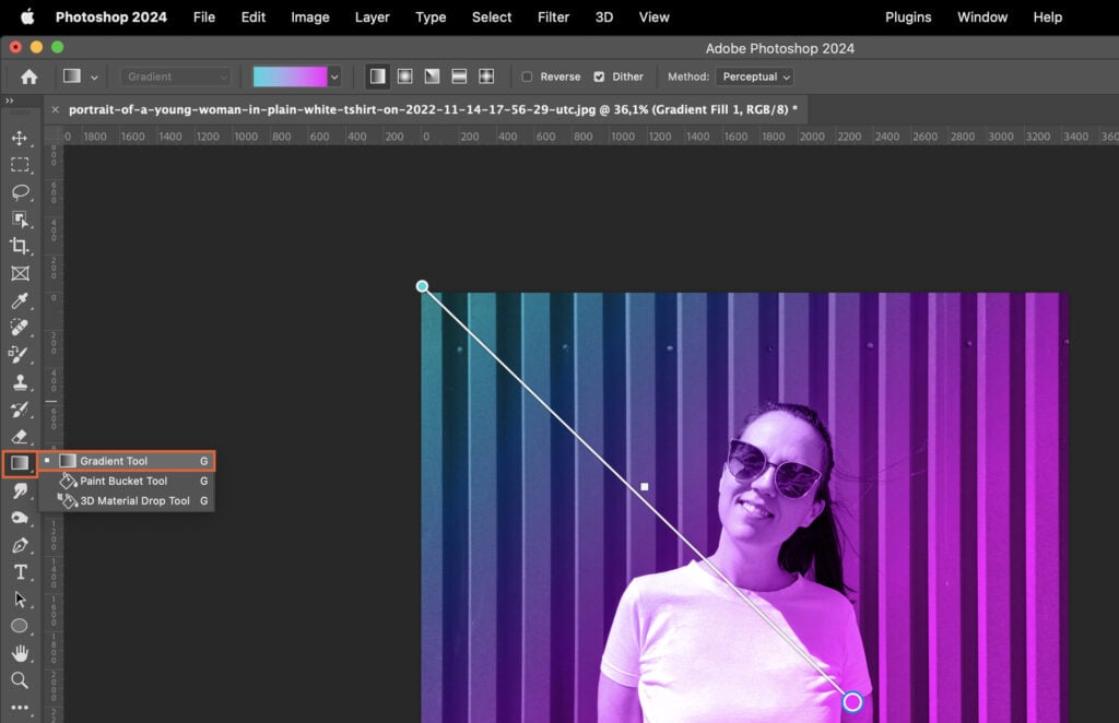 A girl standing in front of a rainbow, with a computer screen displaying the Adobe Photoshop app.