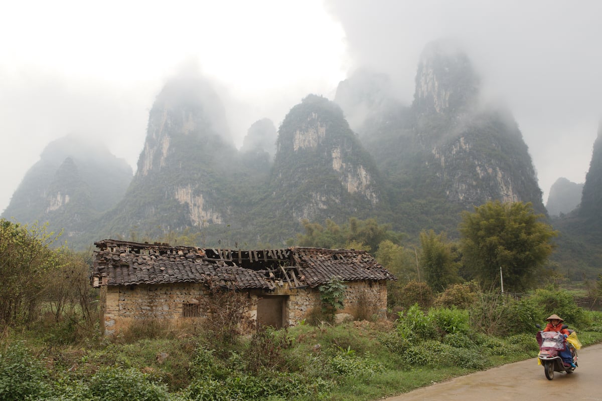 Highlights recovered in a photo of motorcyclist in a rural area with building and karsts using AfterShot Pro 3