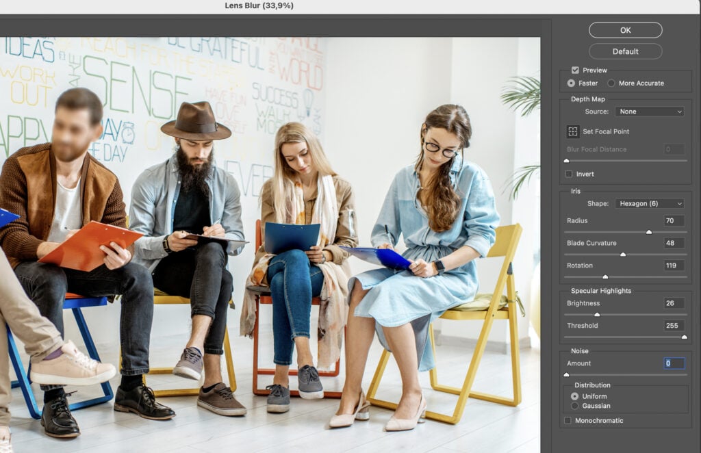 A group of people sitting around chairs and tables while one person is reading something on a tablet.