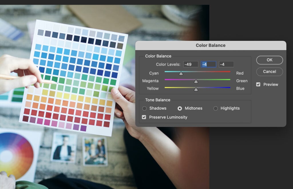 A person holding a color palette on a computer monitor, with a variety of colors displayed.