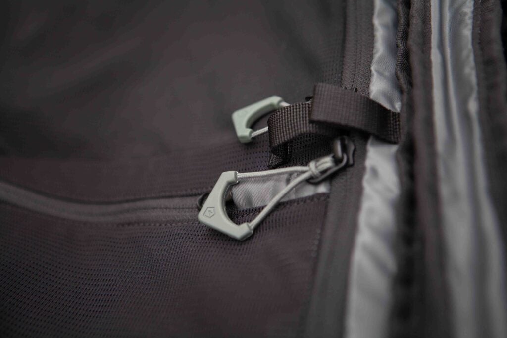 A close up of a black duffel bag with zips, tags and straps.