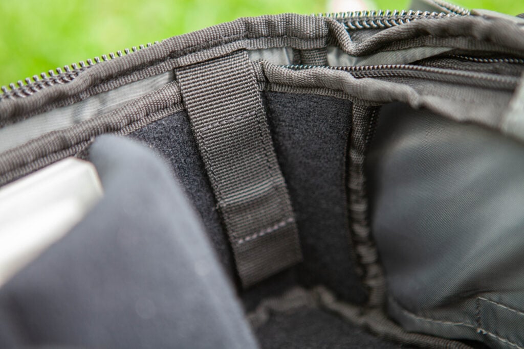 A black carrying case with a gray strap, placed on the grass.