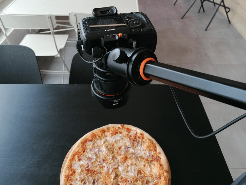A camera on a tripod taking a picture of a pizza