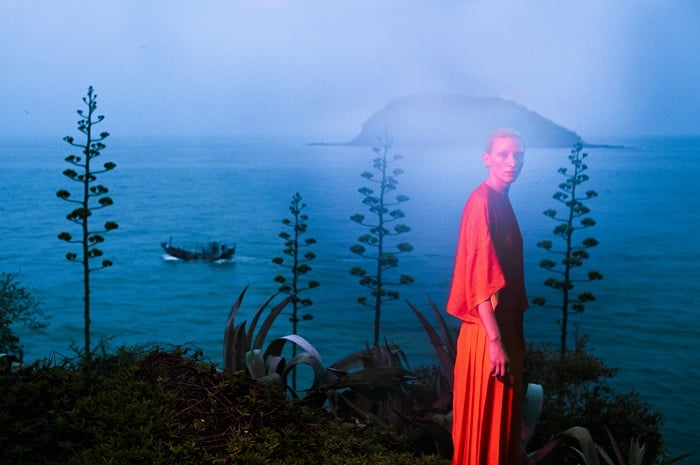 Mysterious image of woman in red near a lake at dusk