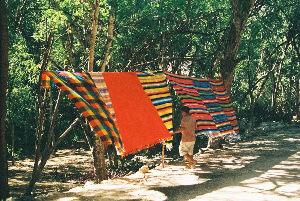 Man escaping between some colorful hanging blankets