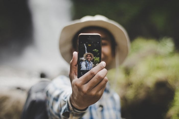 Man in hat taking selfie with a smartphone