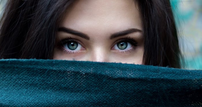 Close portrait of woman covering bottom half of face with scarf