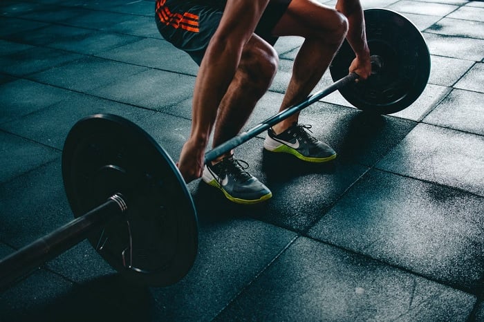 Man squatting about to lift a weighted bar in a gym
