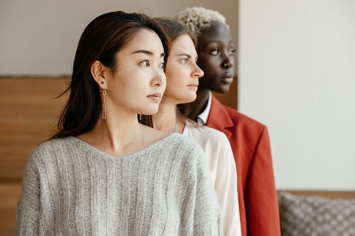 Three multi-facial women standing in line