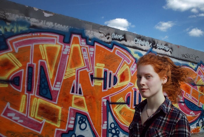 Woman with red hair walking past gaffitied wall