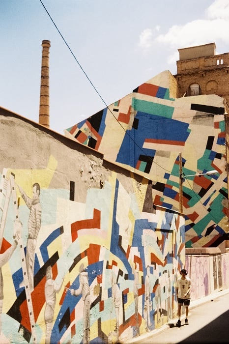 Man walking up a street with colorful, angular graffiti