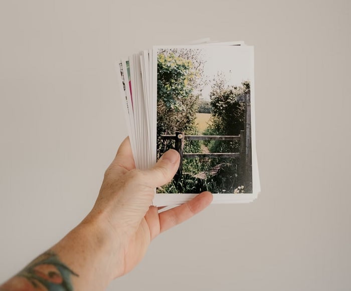 Hand stretched out holding a stack of printed photos
