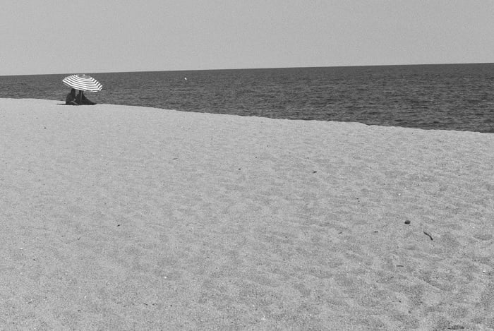 Low-contrast black and white image of single umbrella on a beach