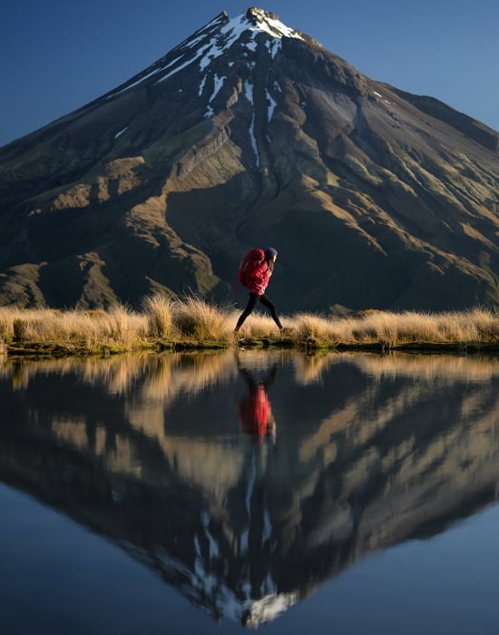 Woman walking by lake with mountain behind