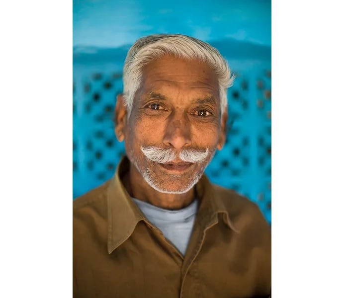 Portrait of man with moustache against blue backdrop
