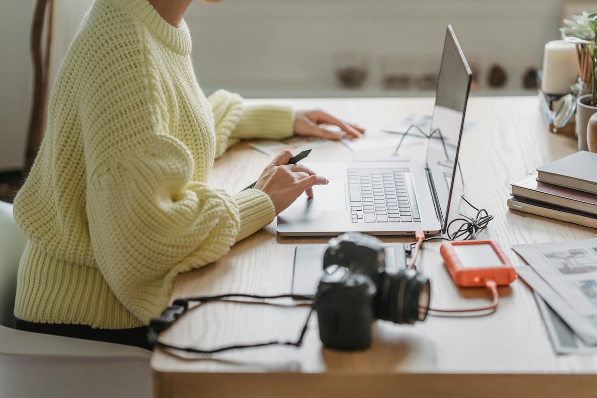 person working at a laptop with camera equipment on desk