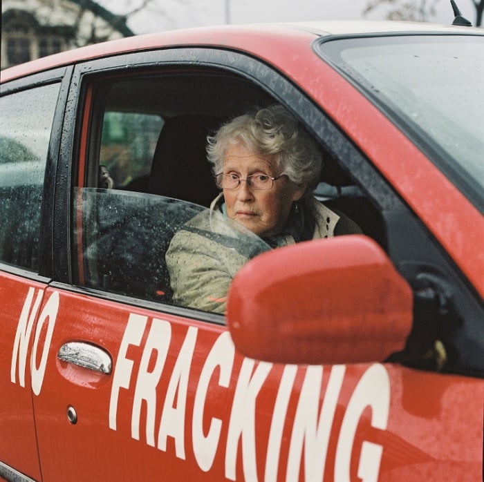 Elderly lady in car with No Fracking on the side