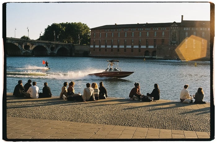Water skier going past people sitting on the river back in Toulouse