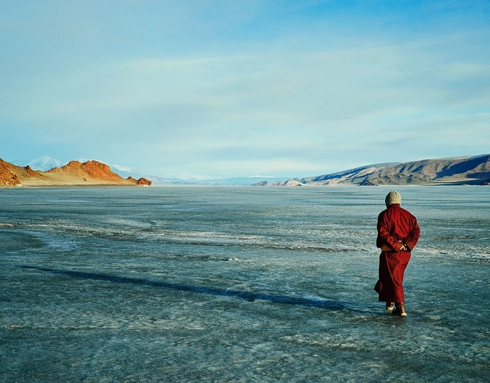 Mongolian monk walking on open ice plane