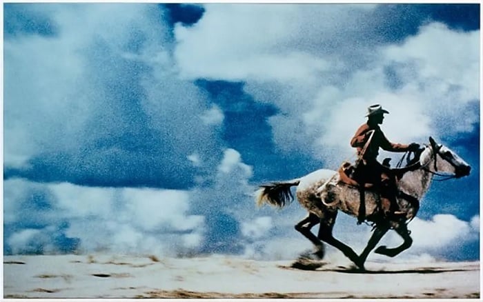Cowboy riding a horse against cloudy sky